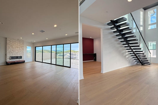 Modern living space with wide plank hardwood flooring, large windows, open staircase