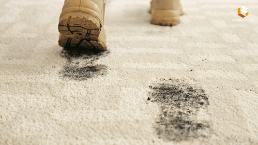 Dirty boots leaving muddy footprints on a light carpet surface