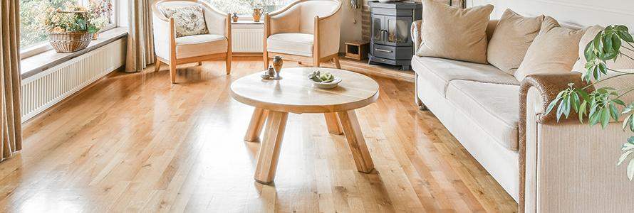 Bright living room with light hardwood flooring, beige sofa, wood coffee table, and armchairs